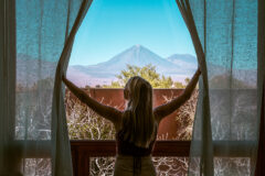 Guest opening the curtains in a guest room, overlooking view of a volcano